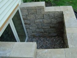Sunken square patio feature with stone block walls and a gravel base, next to a sliding glass door.