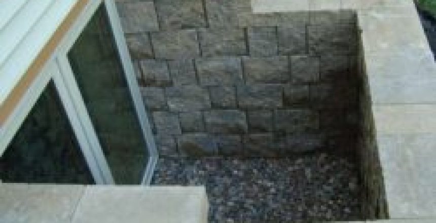 Sunken square patio feature with stone block walls and a gravel base, next to a sliding glass door.