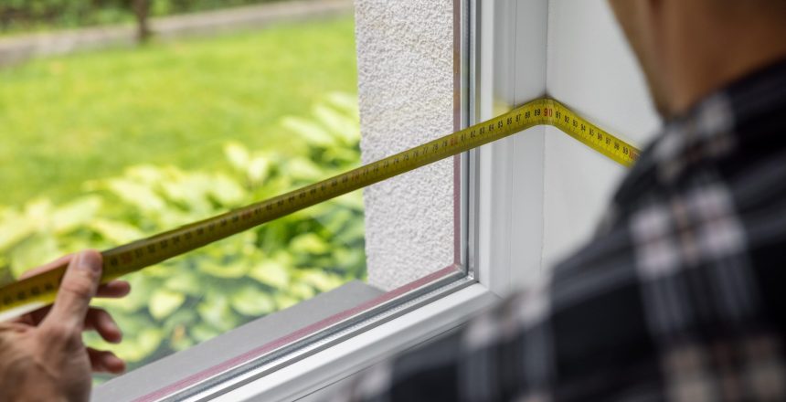man measuring white plastic window frame for replace